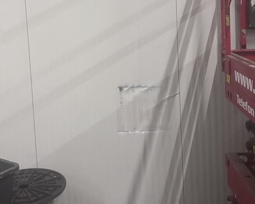 Gesamtansicht des Schadensbereichs in der Halle vor der Reparatur, mit Hubsteiger im Vordergrund.
